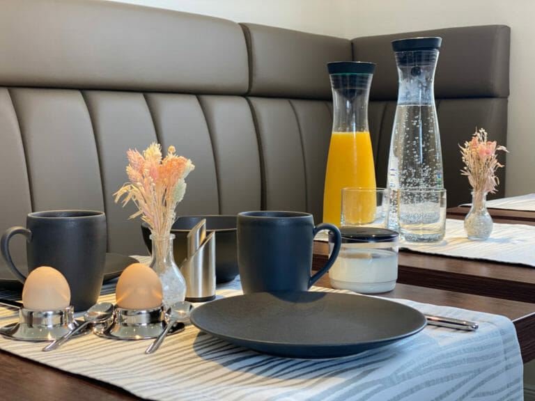 Gedeckter Frühstückstisch mit Wasser- und Orangensaftkaraffe