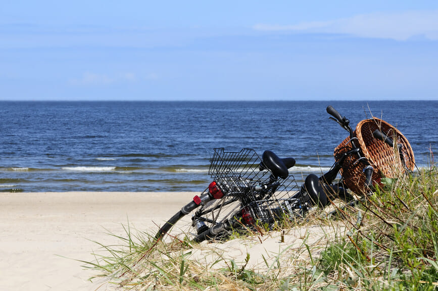 Fahrrad lehnt an Düne mit Meer im Hintergrund