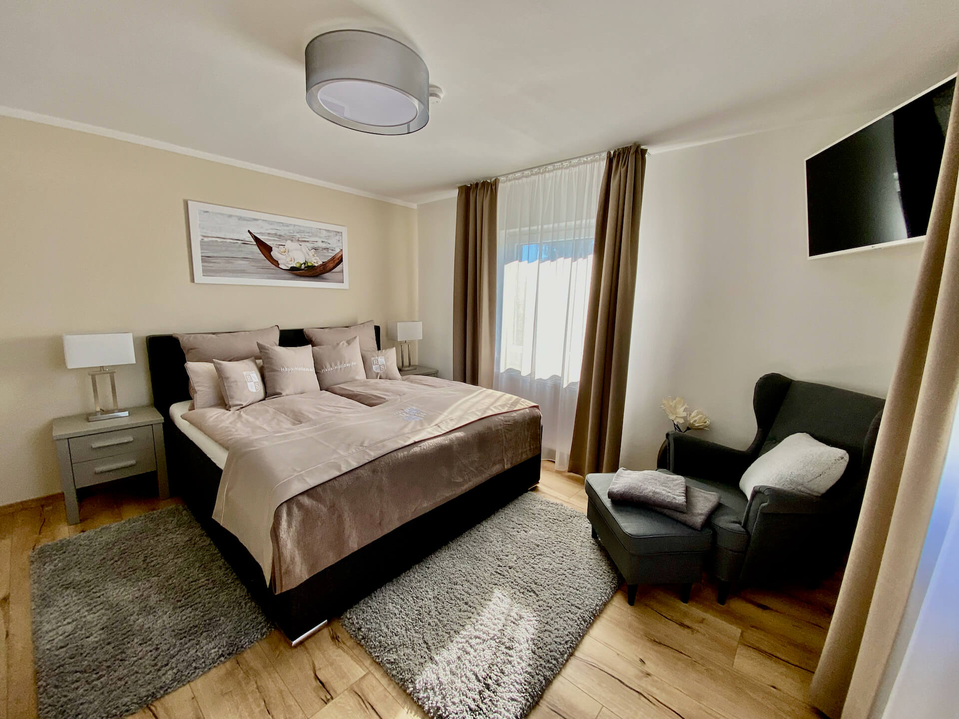 Schlafzimmer mit Doppelbett, Sessel und LED Smart TV